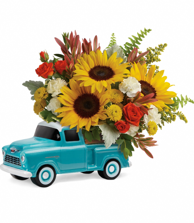 Chevy Pickup Bouquet by Days Flowers Florida, displaying small golden sunflowers, orange spray roses, and green foliage piled high in the back of a vintage hand-glazed ceramic Chevrolet truck container.