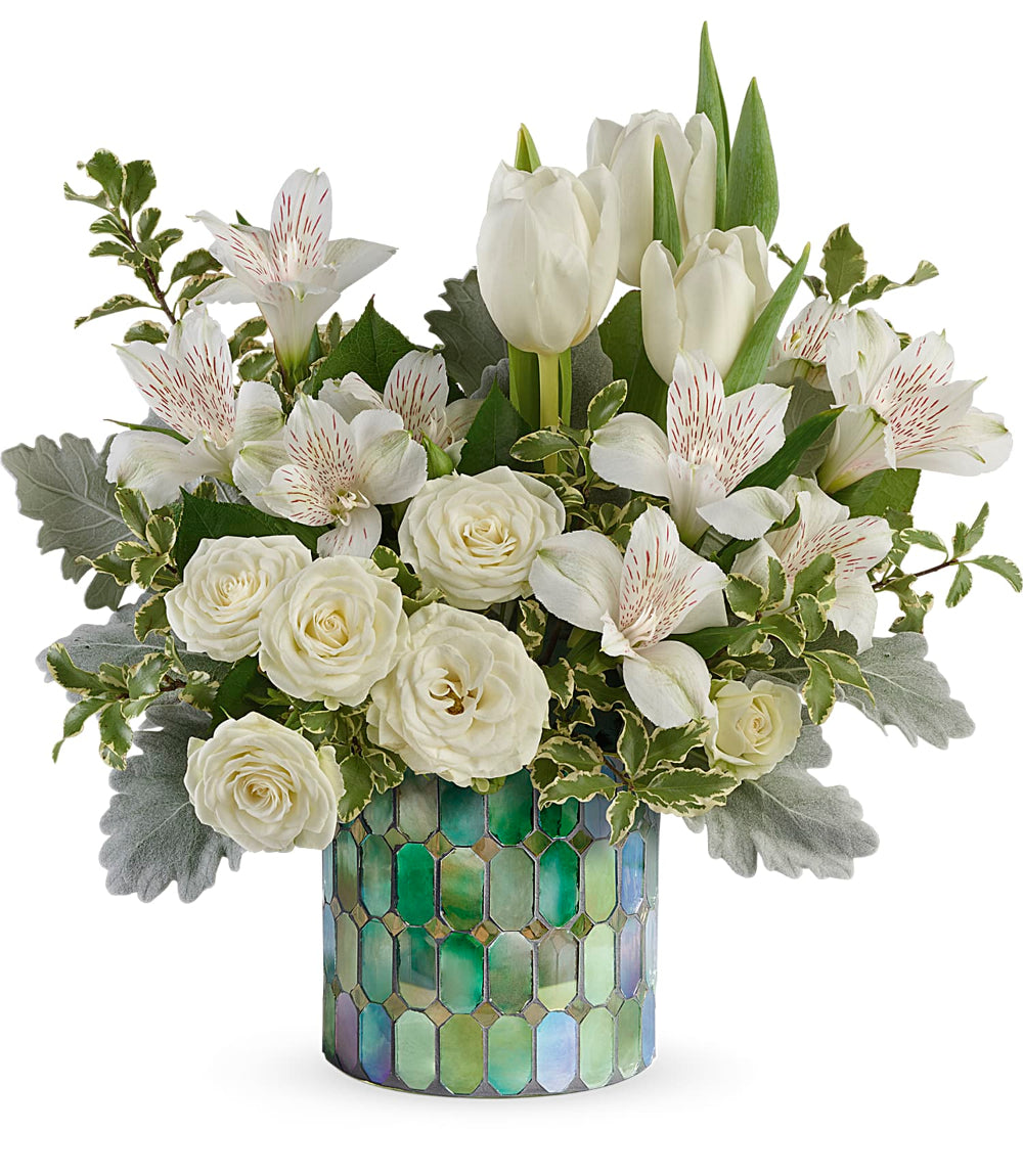 Divine Mosaic Bouquet by Days Flowers Florida featuring white tulips, white alstroemeria, white spray roses, dusty miller, and greenery arranged in a stained glass cylinder vase for a peaceful and elegant floral design.