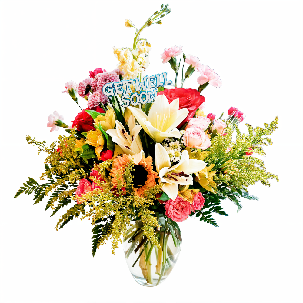 Side view of Healing Sunshine floral display showing the included Get Well Soon card nestled among fresh green foliage and pink carnations.