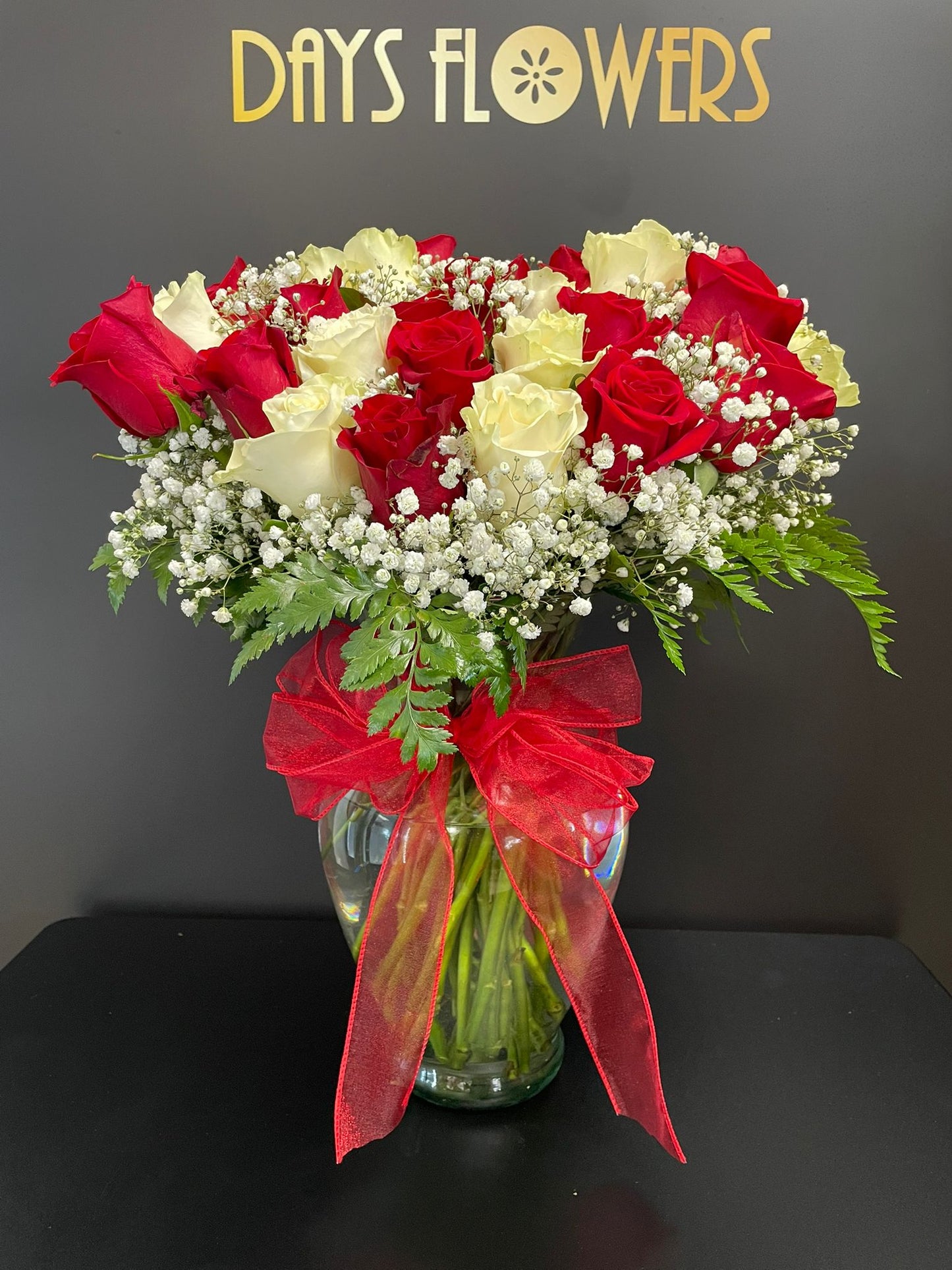 Days Flowers Florida: 48-Rose arrangement with gypsophila and red bow. Pure white and bold red roses symbolize love in Port St. Lucie.