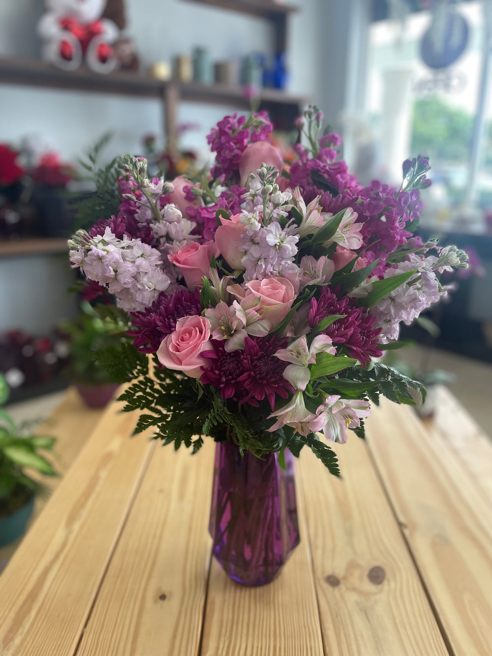 Artistic studio capture of the Steal the Show premium pastel arrangement, showcasing the vibrant lavender and purple hues in a classic transparent glass vessel.
