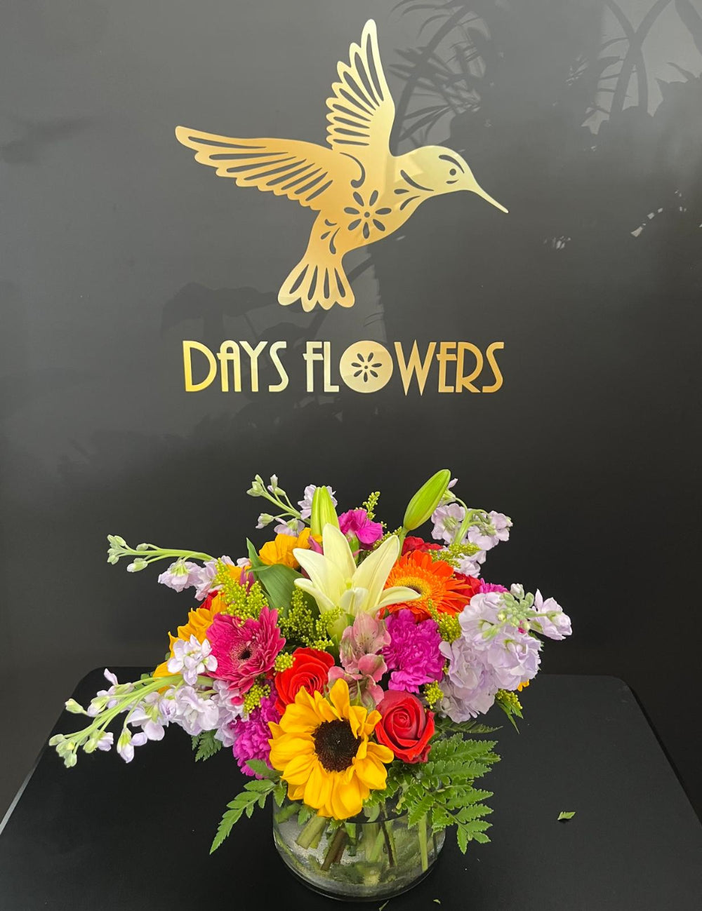 Close-up of the transparent glass vase displaying the thick green stems and bright yellow sunflower petals.