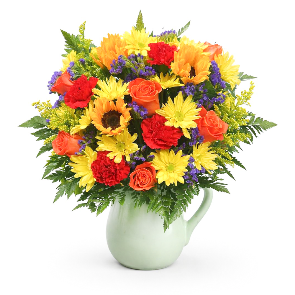 Country Garden Pitcher floral arrangement with a prominent sunflower, orange roses, and yellow daisies in a mint green ceramic jug by Days Flowers Florida.