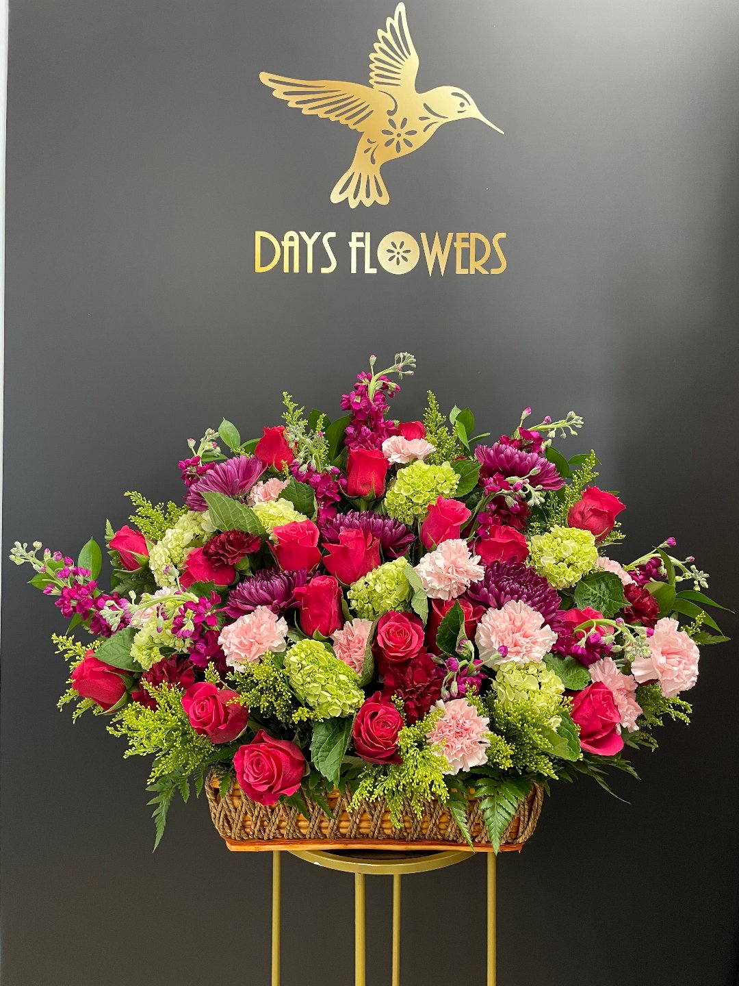 Red roses and greenery in a basket by Days Flowers, delivery in Florida.