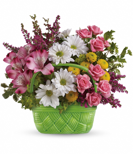 A vibrant floral arrangement in a green basket featuring pink lilies, white daisies, and assorted greenery, perfect for delivery in Summerfield and surrounding areas.