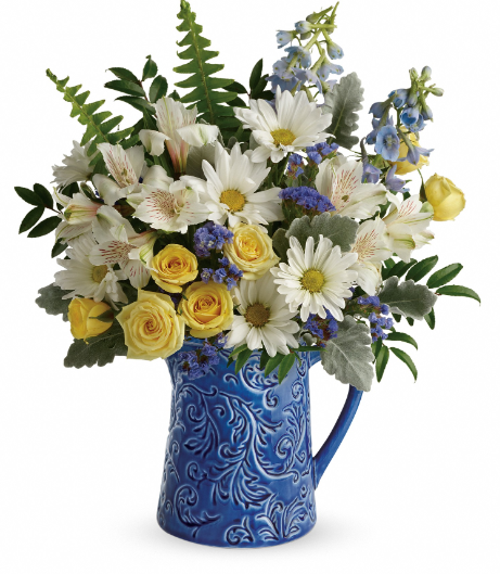 Bright Skies Bouquet by Days Flowers Florida featuring light yellow spray roses, white alstroemeria, blue delphinium, white daisies, blue statice, and fresh greenery in a hand-glazed blue ceramic pitcher