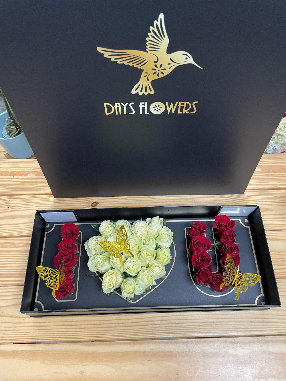 Close-up studio view of the Deep Love Arrangement by Days Flowers Florida, capturing the vibrant crimson and pristine white velvet textures of the roses crafted for unforgettable celebrations.