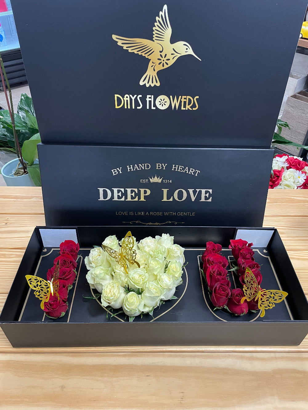 A beautiful top-down perspective of the Deep Love Arrangement from Days Flowers Florida, highlighting the elegant contrast of fifteen white roses and fifteen red roses inside a premium dark box.