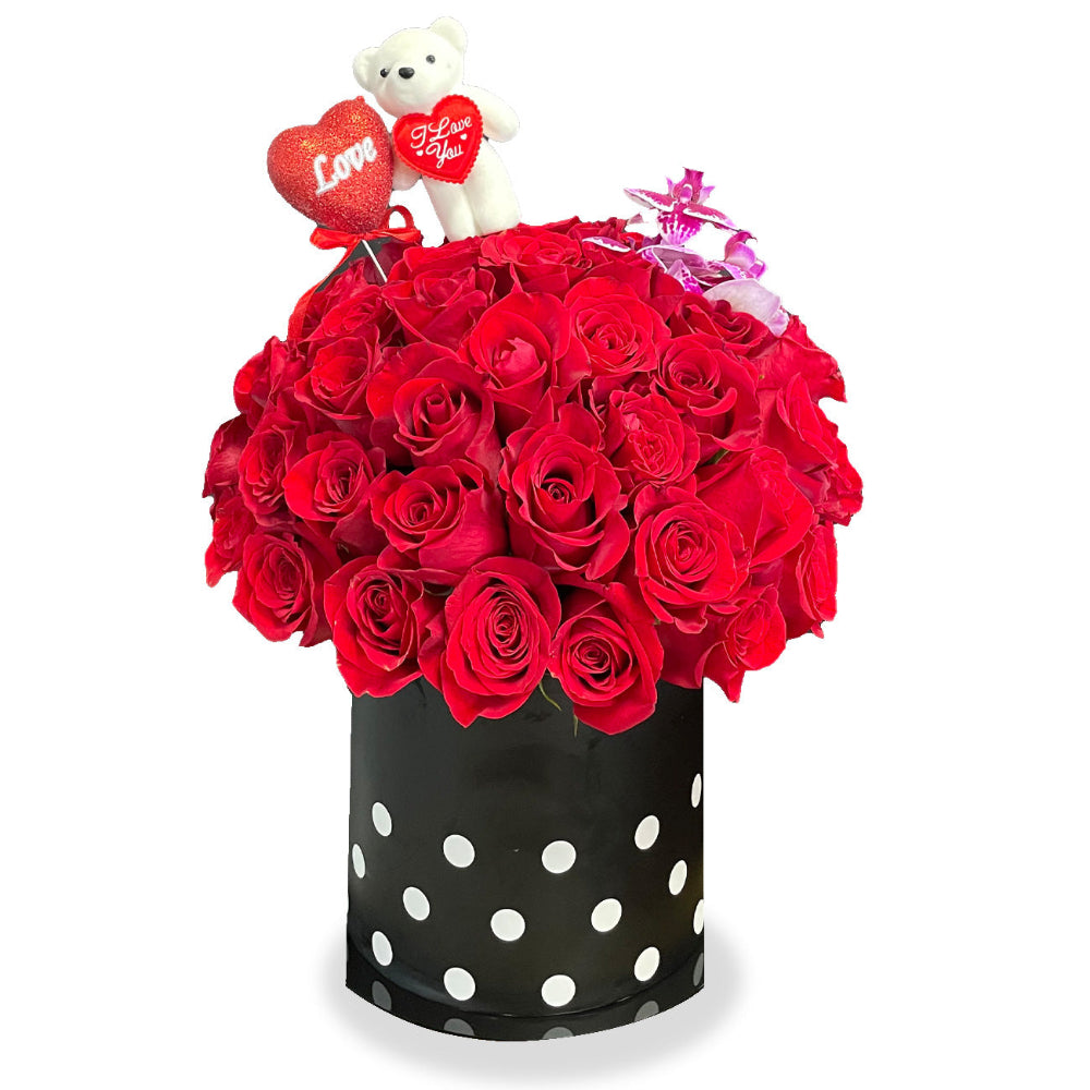 Enchanted Embrace luxury floral arrangement by Days Flowers Florida, displaying an abundant presentation of 50 fresh red roses, an exotic delicate orchid stem, and a cuddly brown plush teddy bear.
