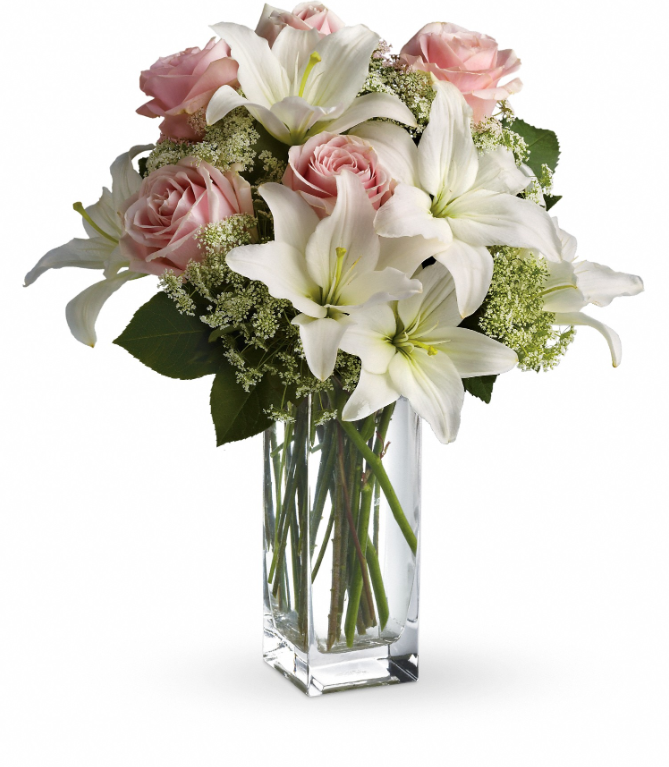Heavenly and Harmony floral centerpiece by Days Flowers Florida, displaying seven long-stemmed light pink roses combined with white Asiatic lilies and Queen Anne's lace inside a tall clear glass vase.