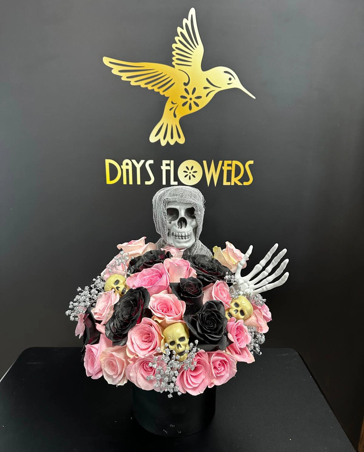Days Flowers Florida: Unique Halloween arrangement capturing the allure of the macabre. Black roses, skulls, and skeleton. Spooky gift delivery in Port St. Lucie.