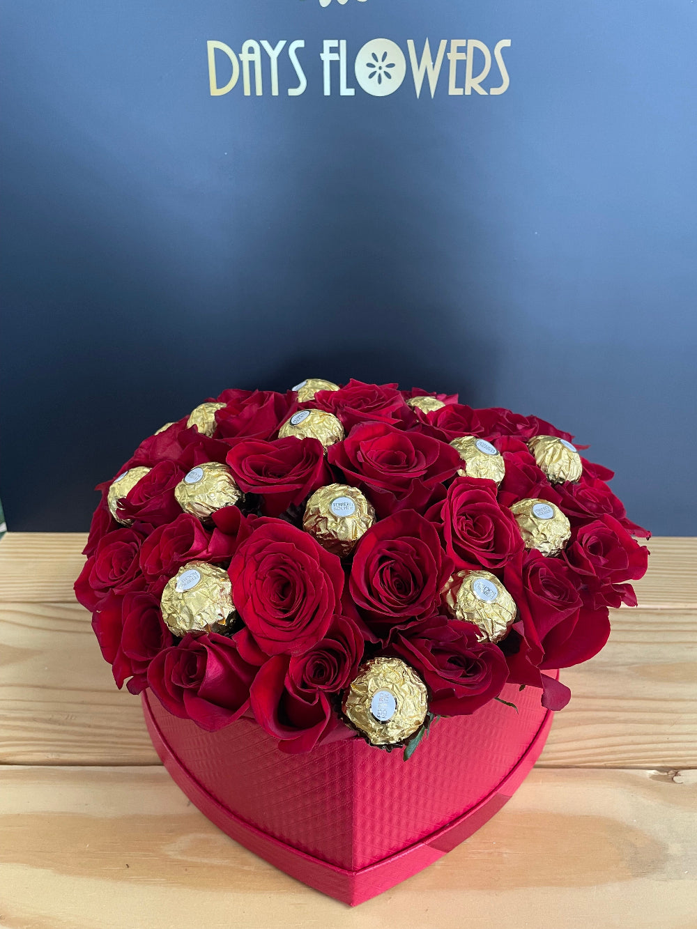 A beautiful top-down perspective of the Romance in a Box arrangement from Days Flowers Florida, highlighting the rich red petals and golden chocolate wrappers in a premium display.