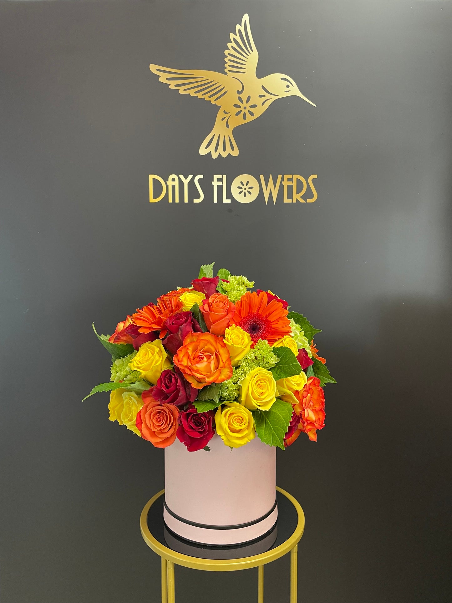 Close-up view of the Sunrise Splendor bouquet by Days Flowers Florida, highlighting the detailed textures of golden yellow blossoms and bright orange Gerbera daisies nested in a luxury white ceramic container.