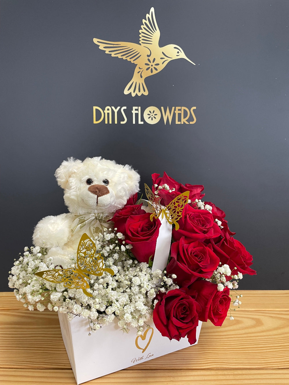 Anniversary gift display featuring the Teddy Love Box by Days Flowers Florida, showcasing the decorative white and golden heart gift container filled with fresh red blooms and a plush toy.
