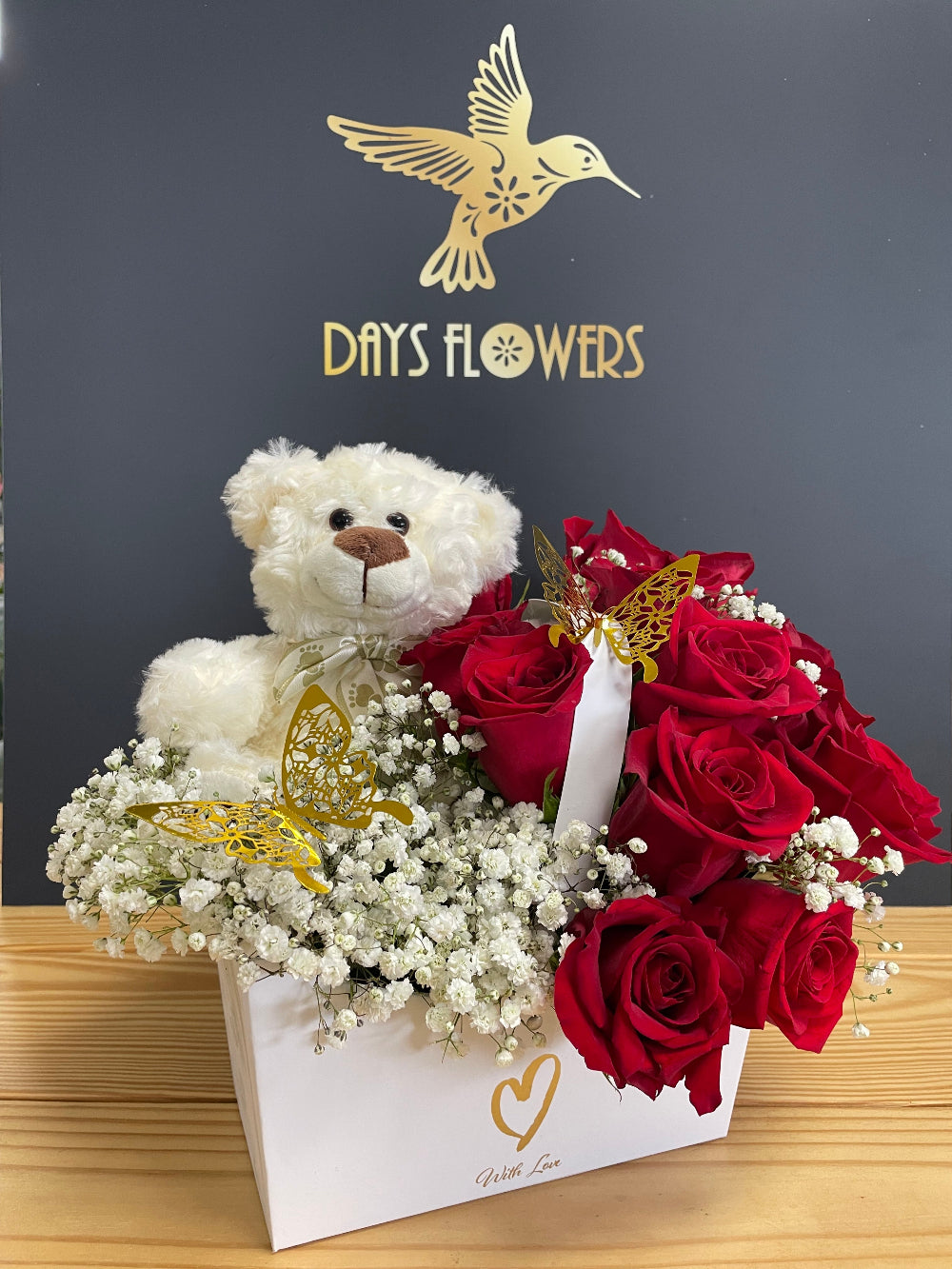 A beautiful top-down view of the Teddy Love Box from Days Flowers Florida, highlighting the rich red petals of the fresh roses contrasted against delicate white baby's breath flowers.