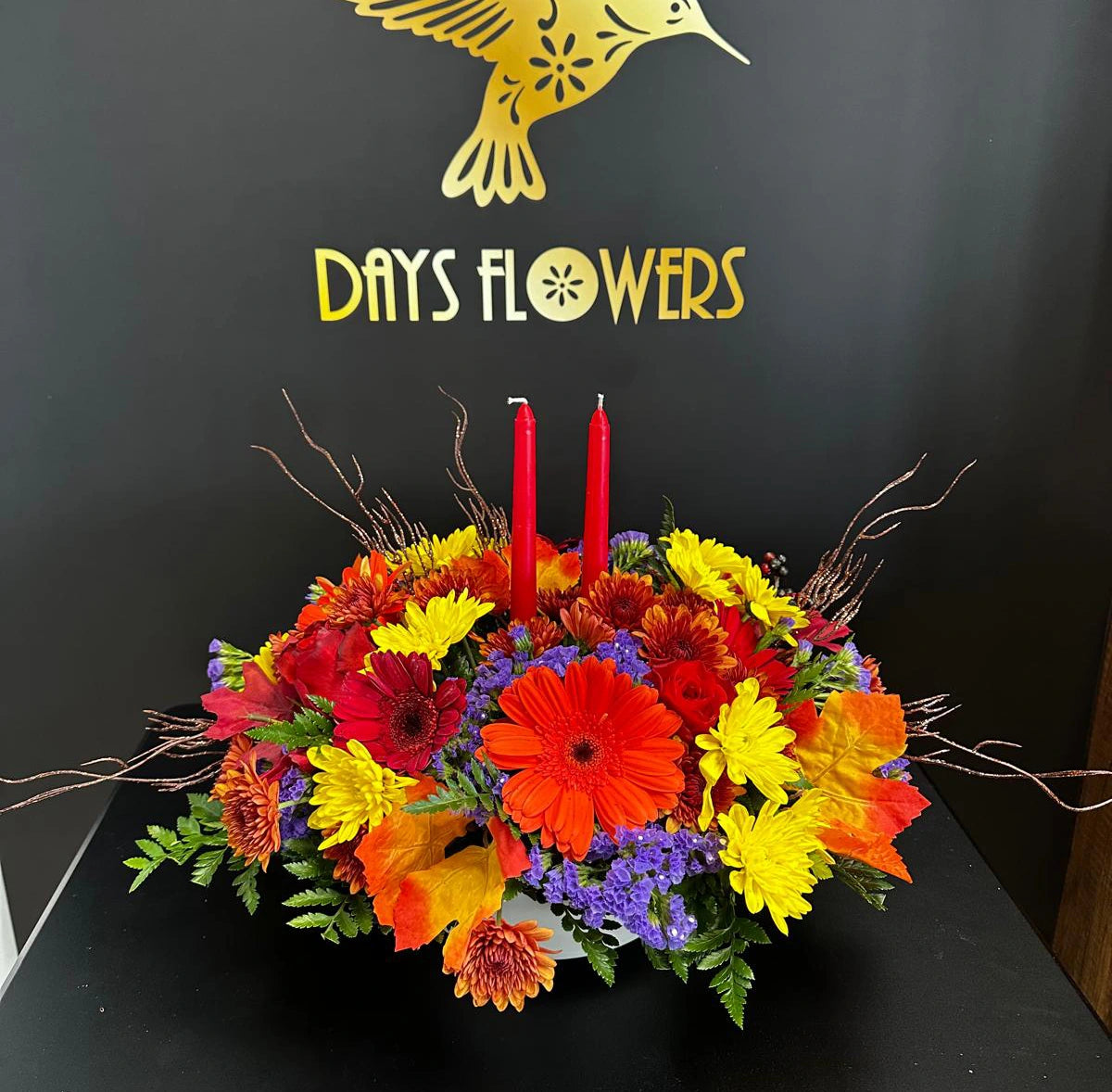 Days Flowers Florida: Festive table centerpiece with warm-toned flowers and red candles. Harvest season arrangement delivered in Ocala, Florida.