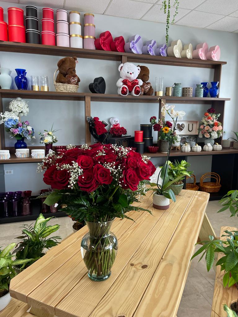 Top-down perspective of the Birthday Arrangement showing opening red roses surrounded by botanical greenery.