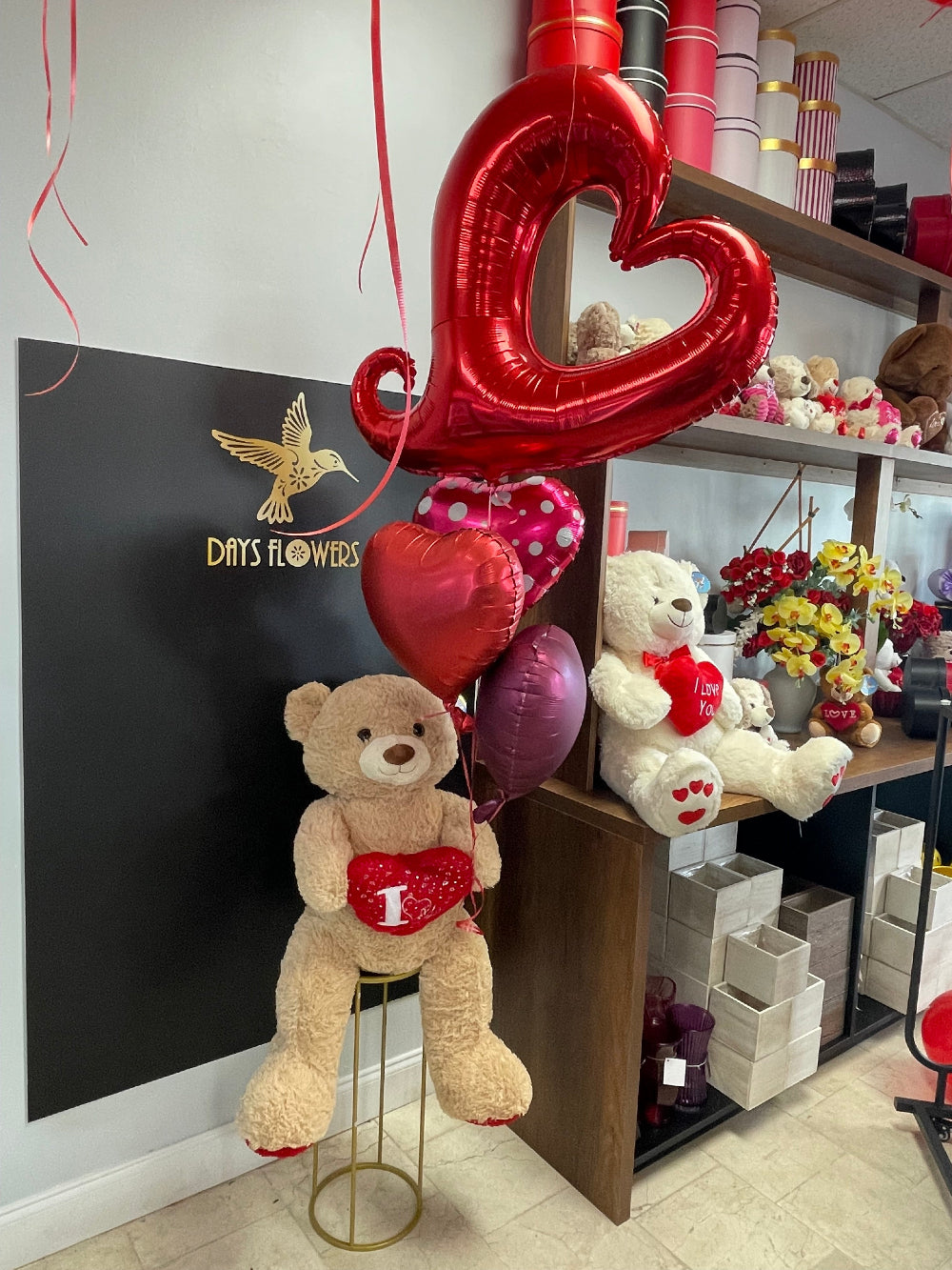 Close-up of the big brown plush teddy bear holding a red heart-shaped cushion.