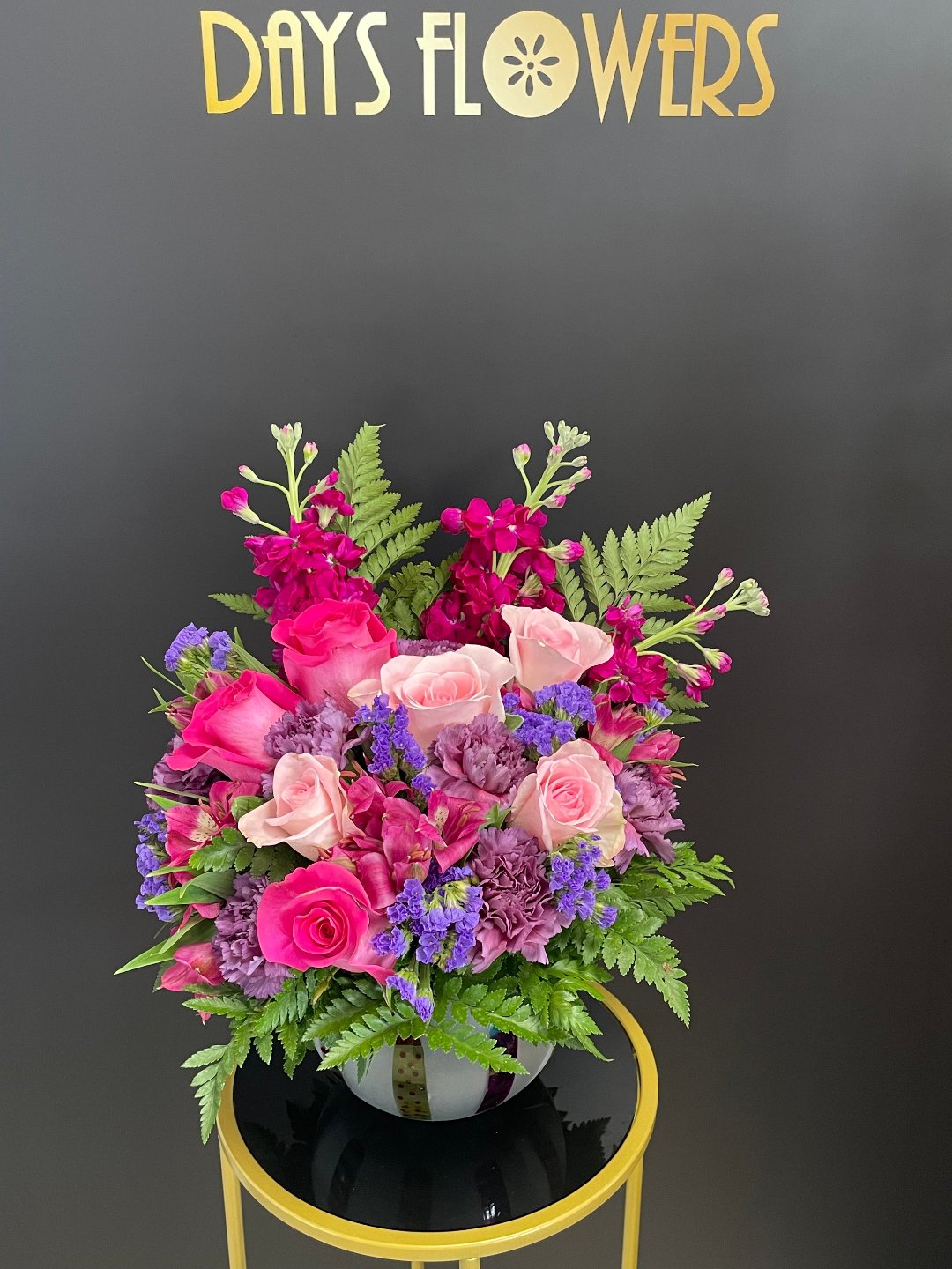 Pink roses and purple flowers in black vase by Days Flowers, delivery in Florida.