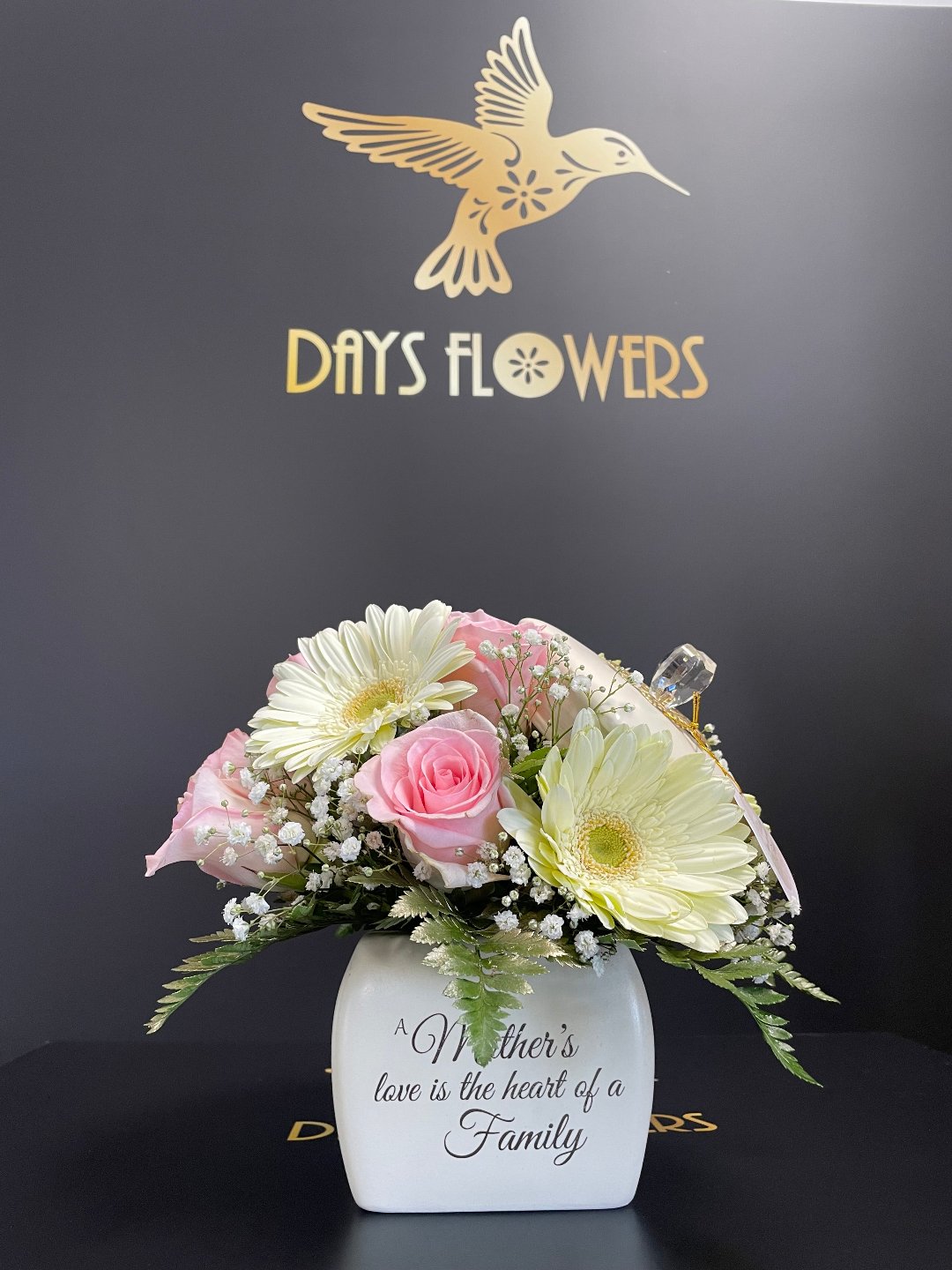 Elegant white and pink floral arrangement in a vase with “Mother’s love is the heart of a Family” inscription, by Days Flowers, free delivery in Florida areas including Ocala, Orlando, The Villages, and Port St. Lucie.