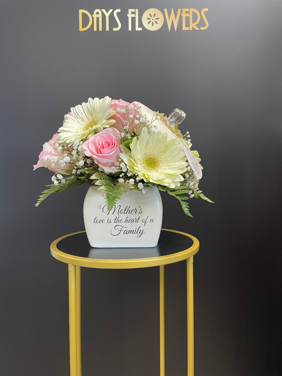 Elegant white and pink floral arrangement with “A Mother’s love” inscription, available for free delivery in Summerfield, Ocala, Orlando, The Villages, and Port St. Lucie.