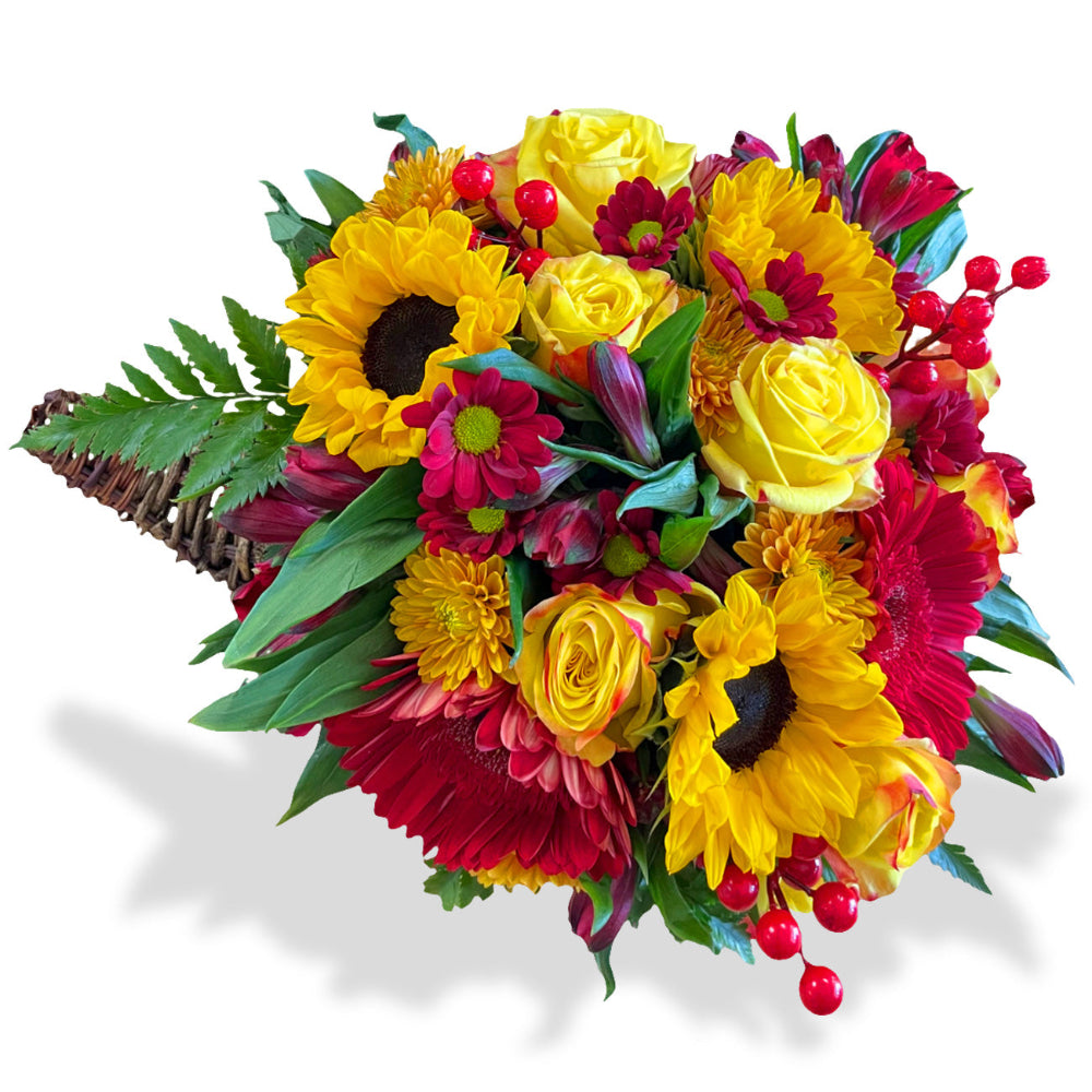 Golden Autumn Centerpiece featuring red roses, yellow chrysanthemums, and orange daisies spilling from a wicker cornucopia basket by Days Flowers Florida
