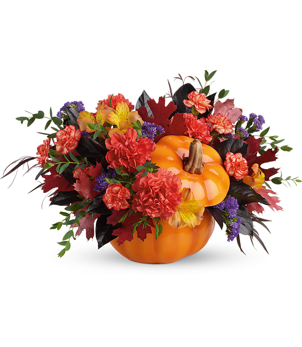 Hauntingly Pretty Pumpkin Bouquet featuring dark orange carnations, purple statice, and preserved red oak leaves in a glazed orange ceramic pumpkin by Days Flowers Florida.