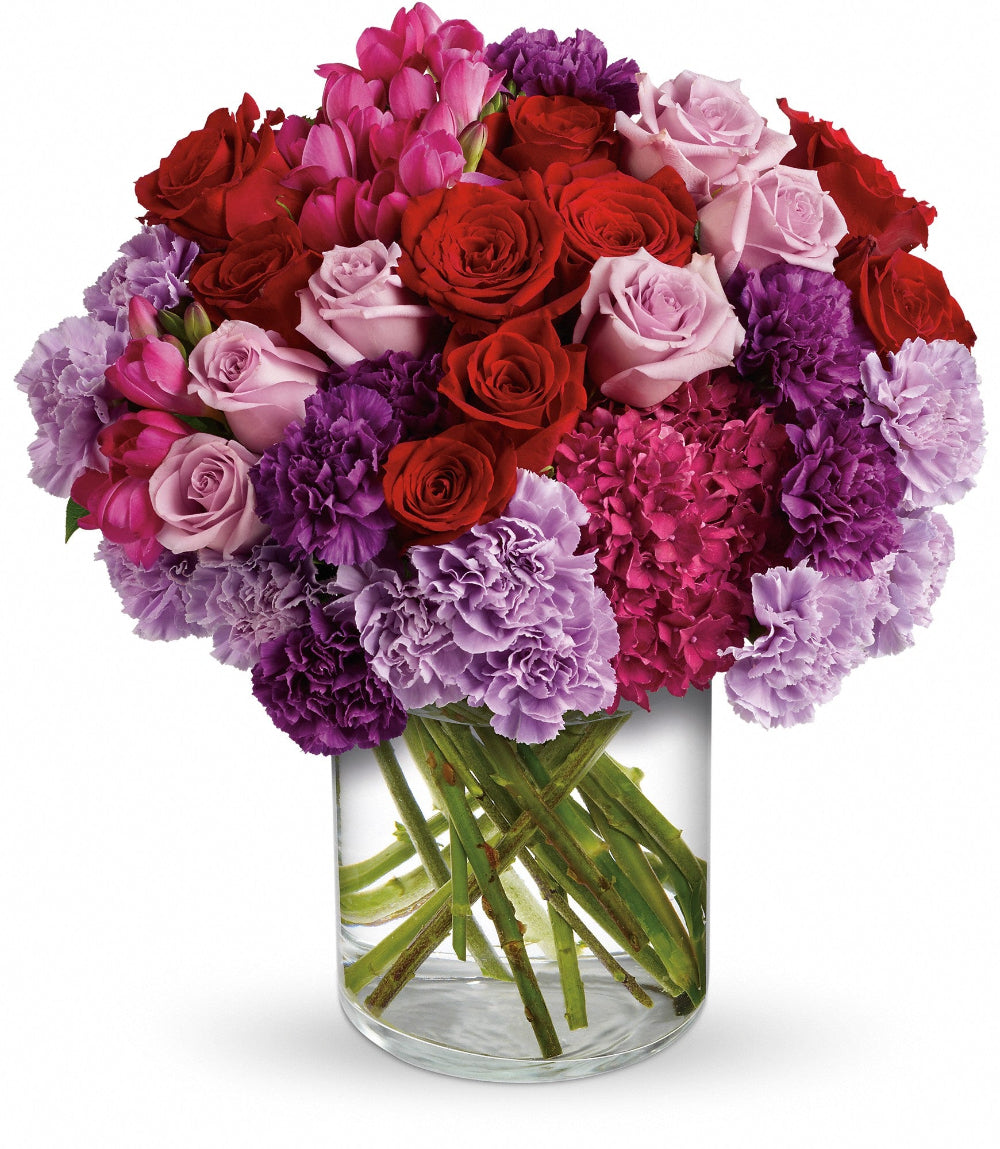 Close-up of the 5x8 clear glass cylinder vase displaying long rose stems and fresh hot pink freesia blooms