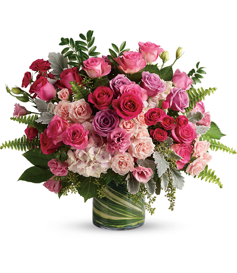 Close-up of the 5x8 clear glass cylinder vase displaying long rose stems and folded variegated aspidistra leaves