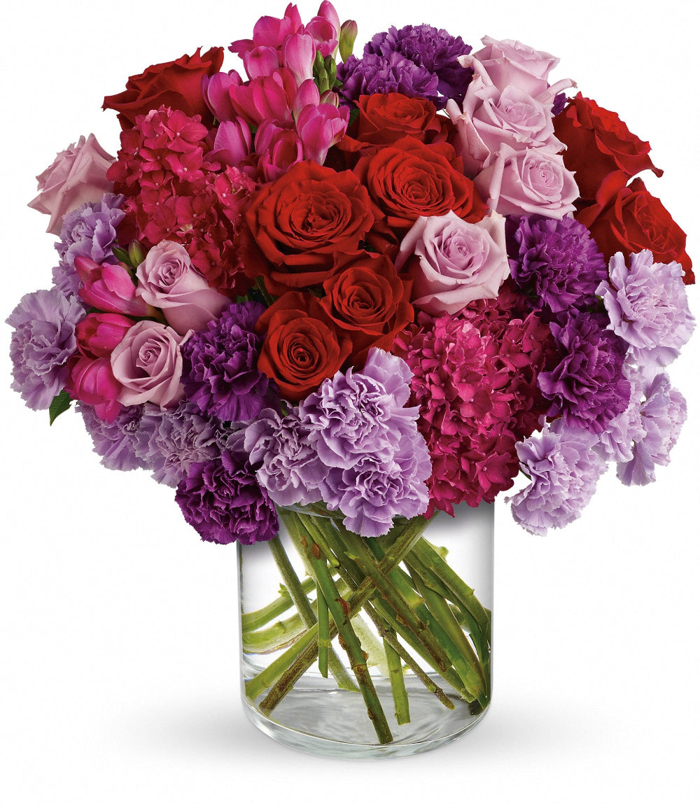 Top-down perspective of the Roman Holiday arrangement showing opening red roses, lavender phlox, and dark pink hydrangeas