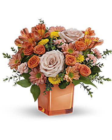 Orange Splendor Bouquet featuring light orange roses, coral spray roses, peach alstroemeria, and yellow button mums in a coral glass cube vase by Days Flowers Florida.
