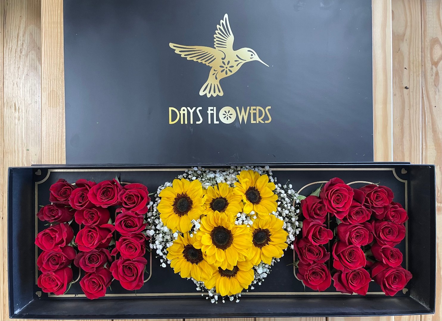 Red roses and sunflowers with baby’s breath in black box by Days Flowers, delivery in Florida.