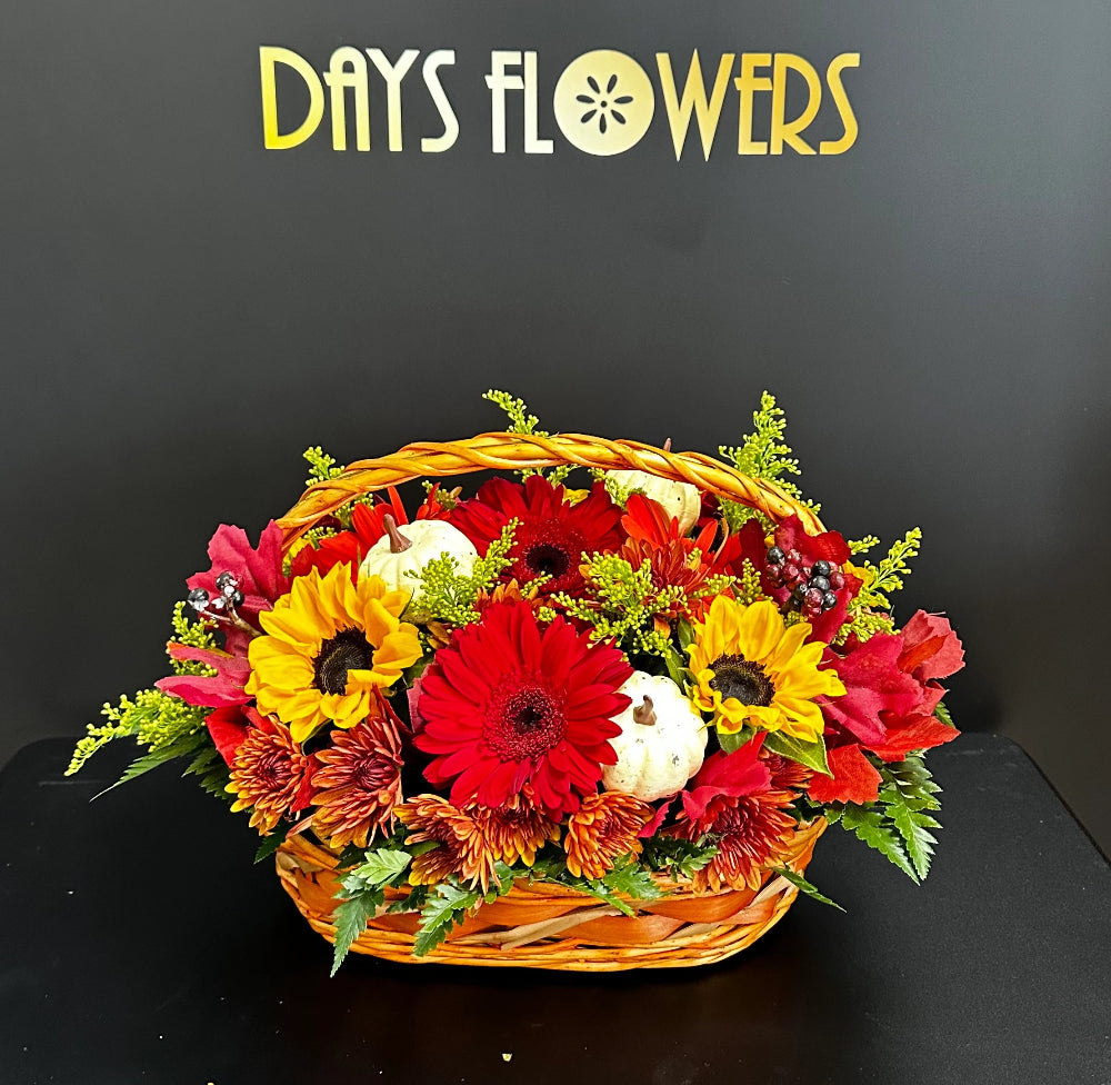 Close-up of the rustic woven basket displaying radiant sunflowers, orange gerberas, and fall foliage.