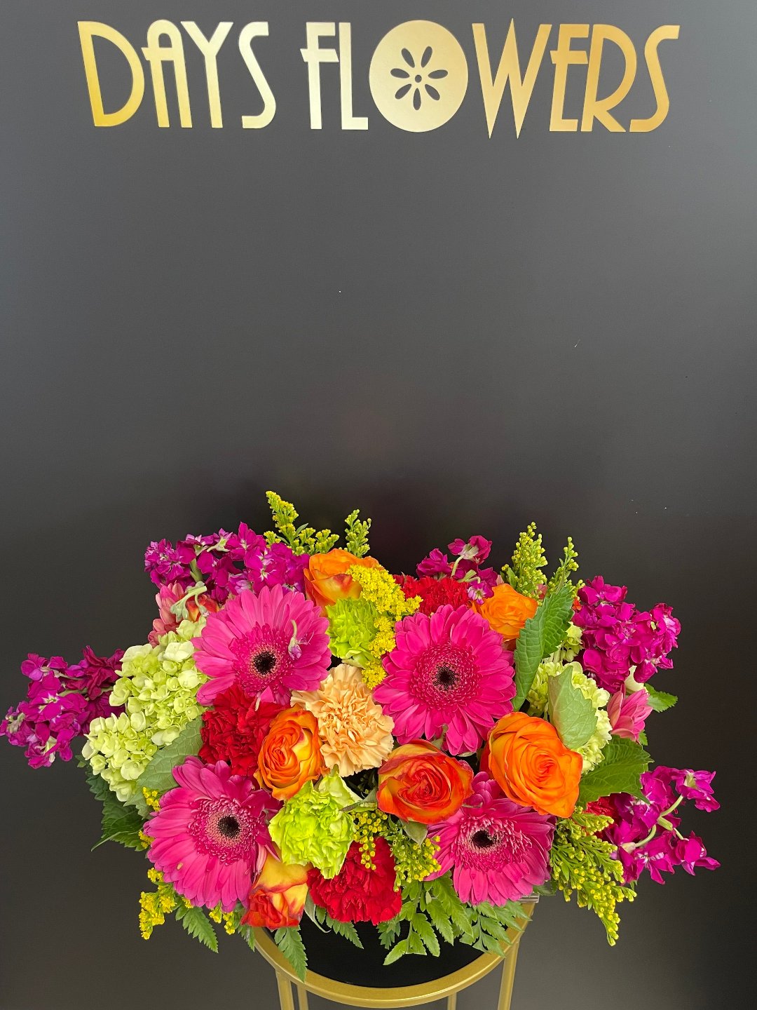 Top-down perspective of the Burst of Beauty arrangement highlighting the dense placement of hot pink dahlias and light orange spray roses