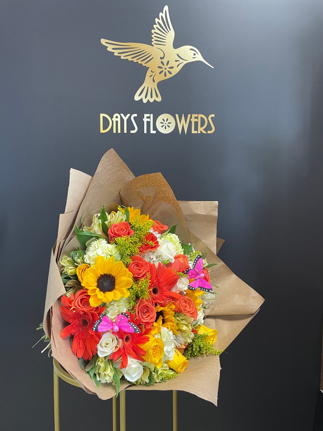 Sunflowers and red gerberas bouquet wrapped in brown paper by Days Flowers, delivery in Florida.