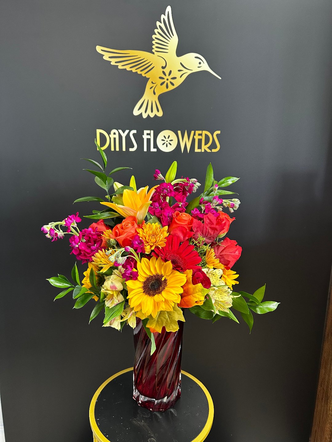 Vibrant sunflower centerpiece in a faceted ruby vase, perfect gift from Day’s Flowers in Florida.