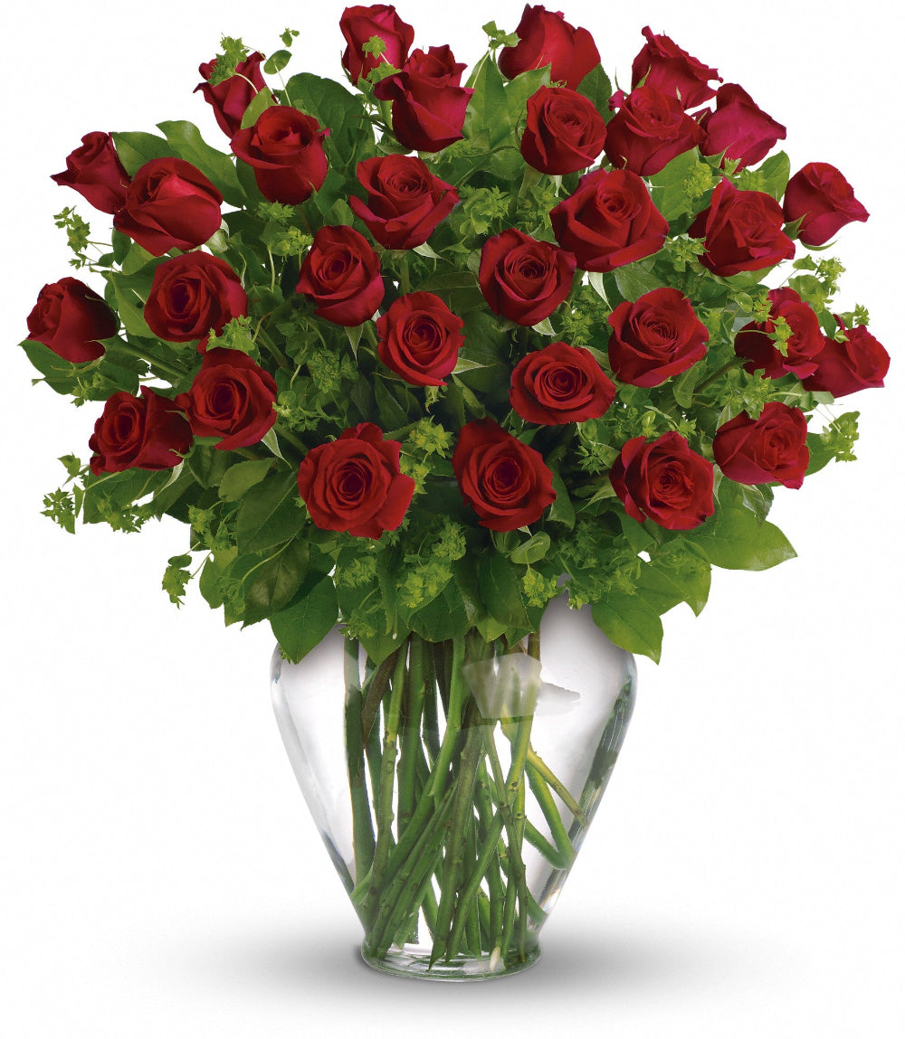 Close-up of the 8-inch clear Athena glass vase displaying thick 60cm red rose stems and green bupleurum foliage