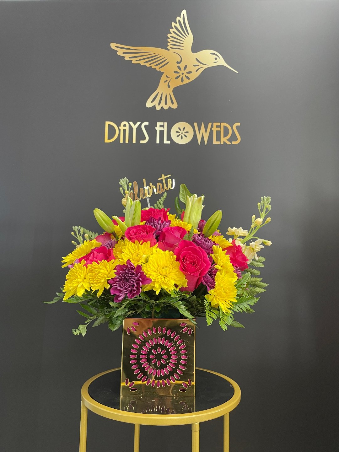 Close-up of the gleaming gold punched pattern cube vase displaying hot pink spray roses and seeded eucalyptus foliage