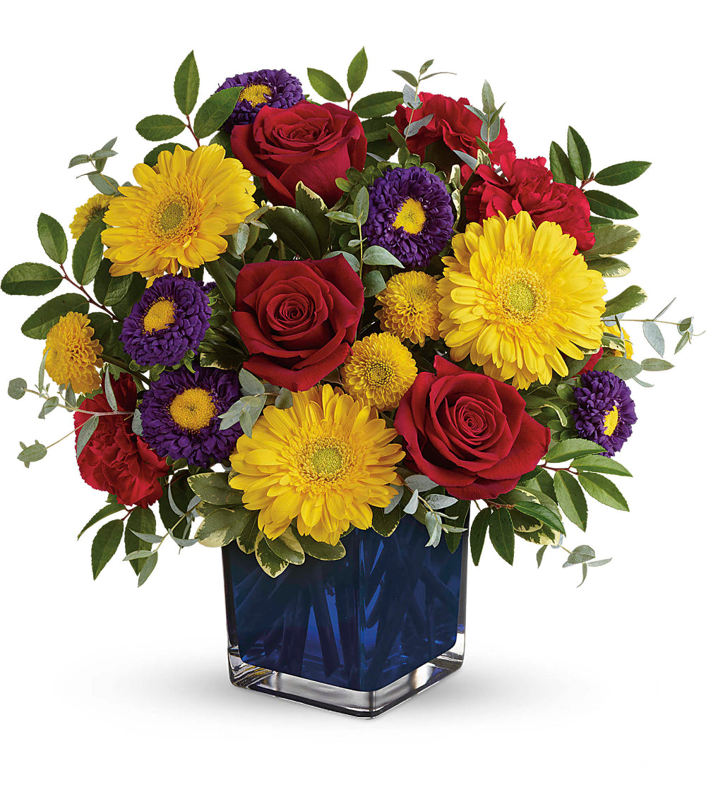 Close-up of the cobalt blue glass cube vase displaying purple matsumoto asters and parvifolia eucalyptus foliage