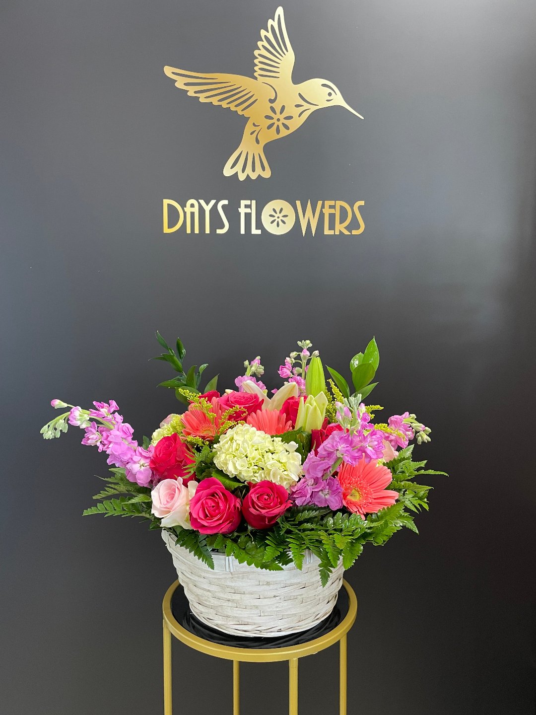 Vibrant floral arrangement by Days Flowers with pink roses, purple accents, and lush greenery in a white basket, perfect for delivery in Summerfield, Ocala, Orlando, The Villages, and Port St. Lucie.