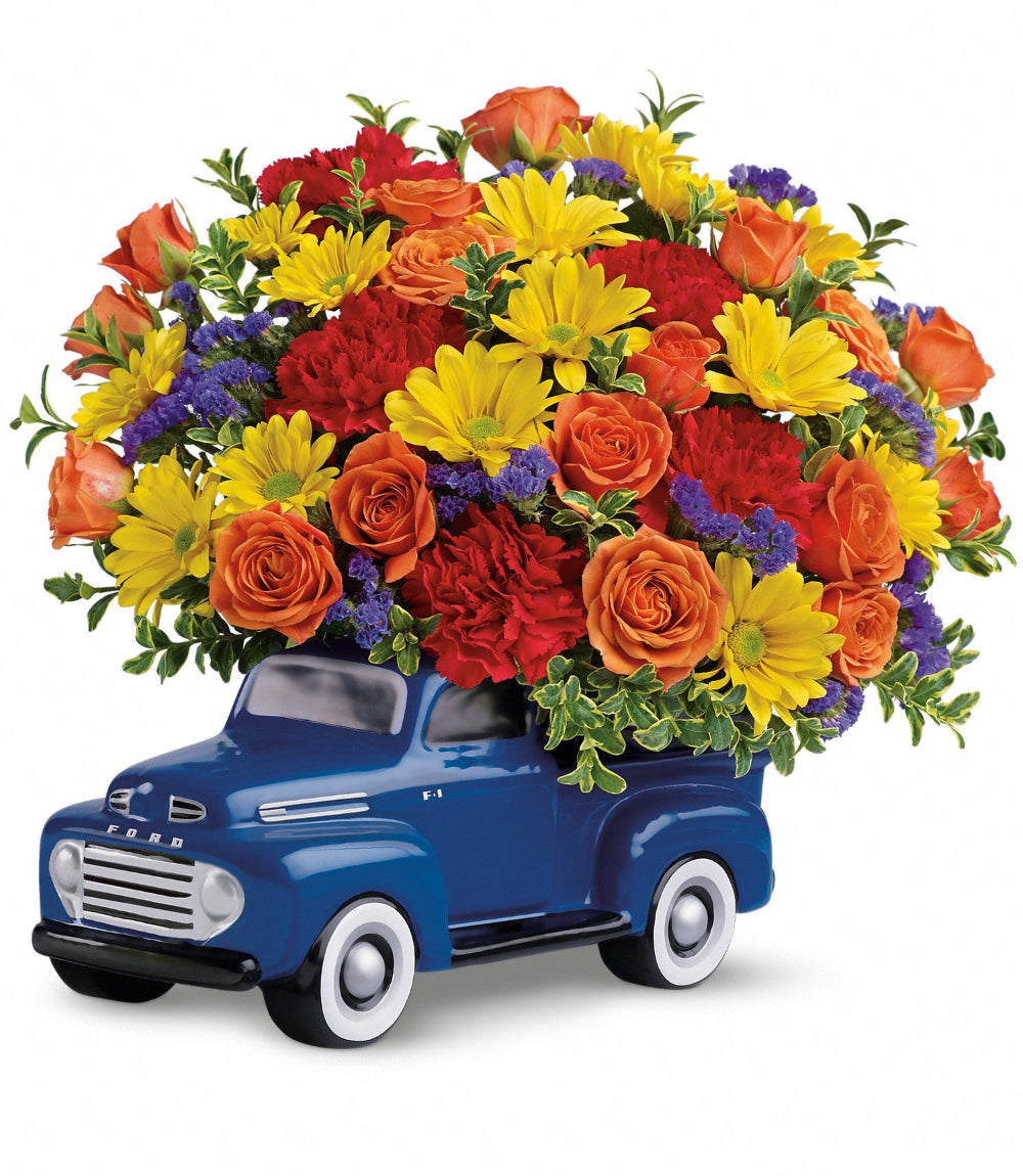 '48 Ford Pickup Bouquet by Days Flowers Florida featuring orange spray roses, red carnations, yellow daisy chrysanthemums, and purple statice arranged in a collectible blue 1948 Ford pickup keepsake.